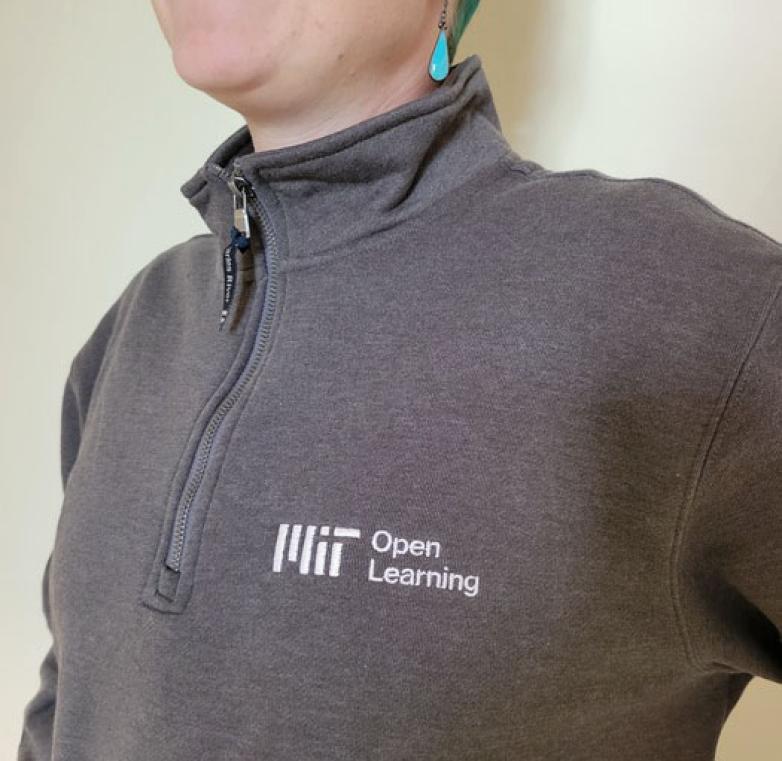 Person wearing a gray zippered fleece jacket with the MIT Open Learning logo in white.
