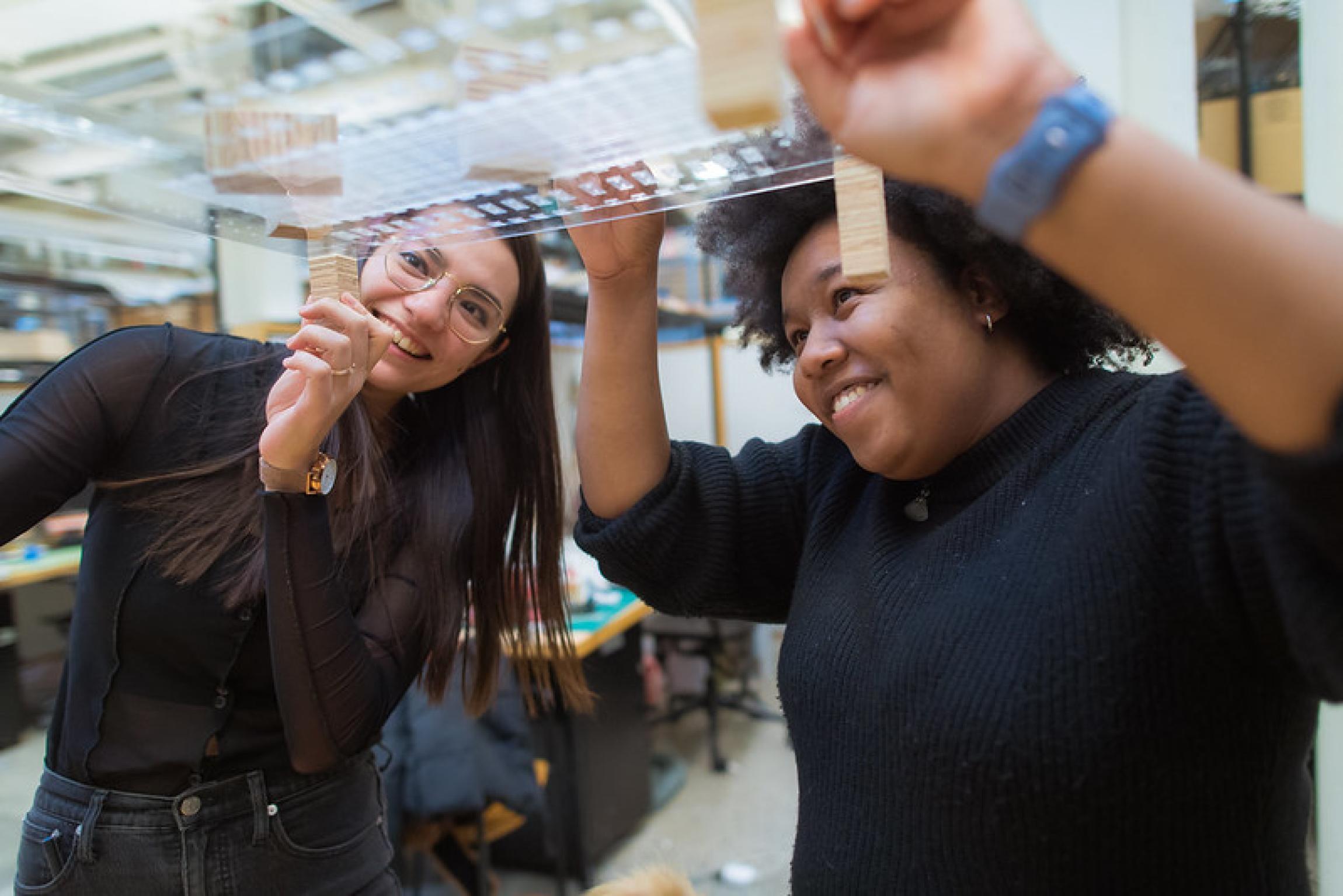 Two students from the School of Architecture and Planning hold up a model.