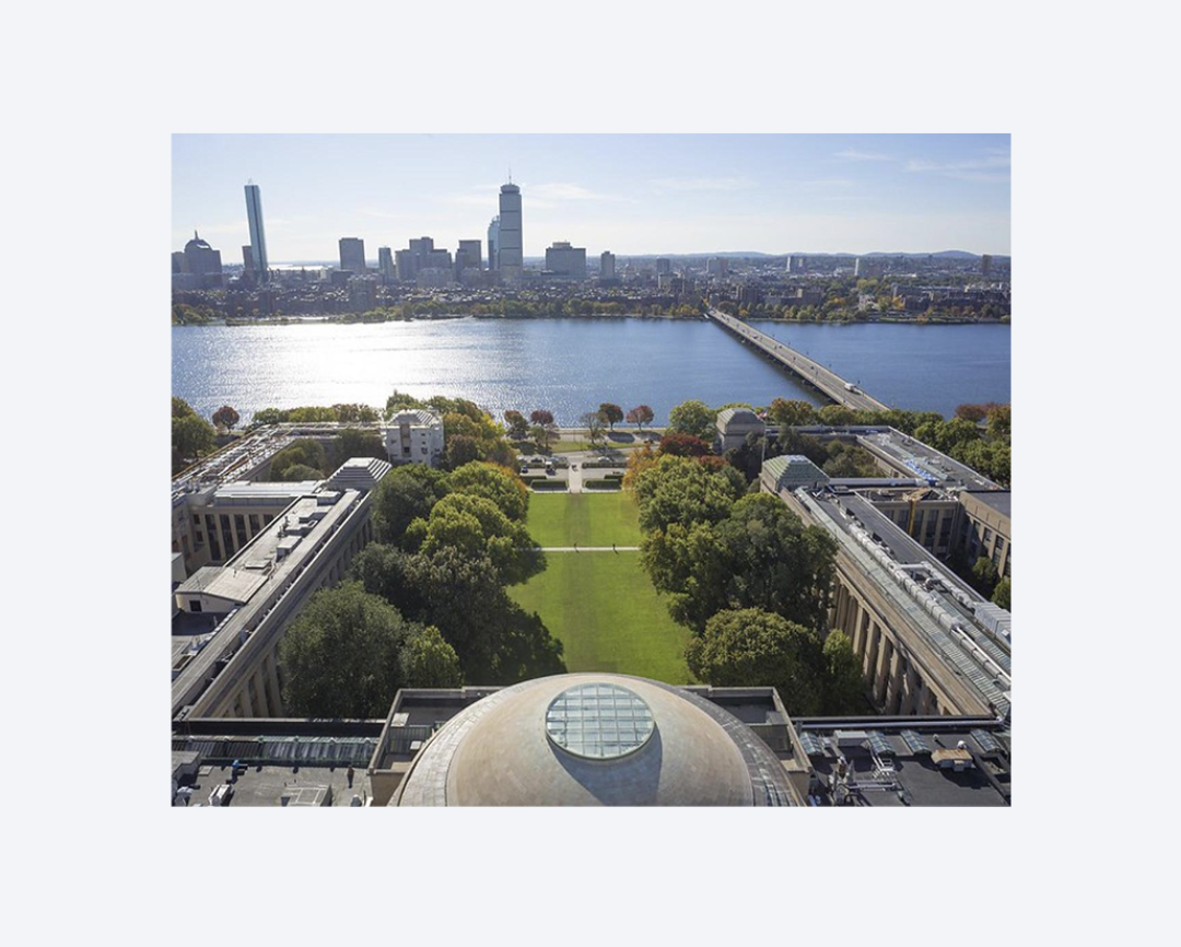 Aerial view of the MIT Dome, with the Charles River and Boston skyline in the distance.